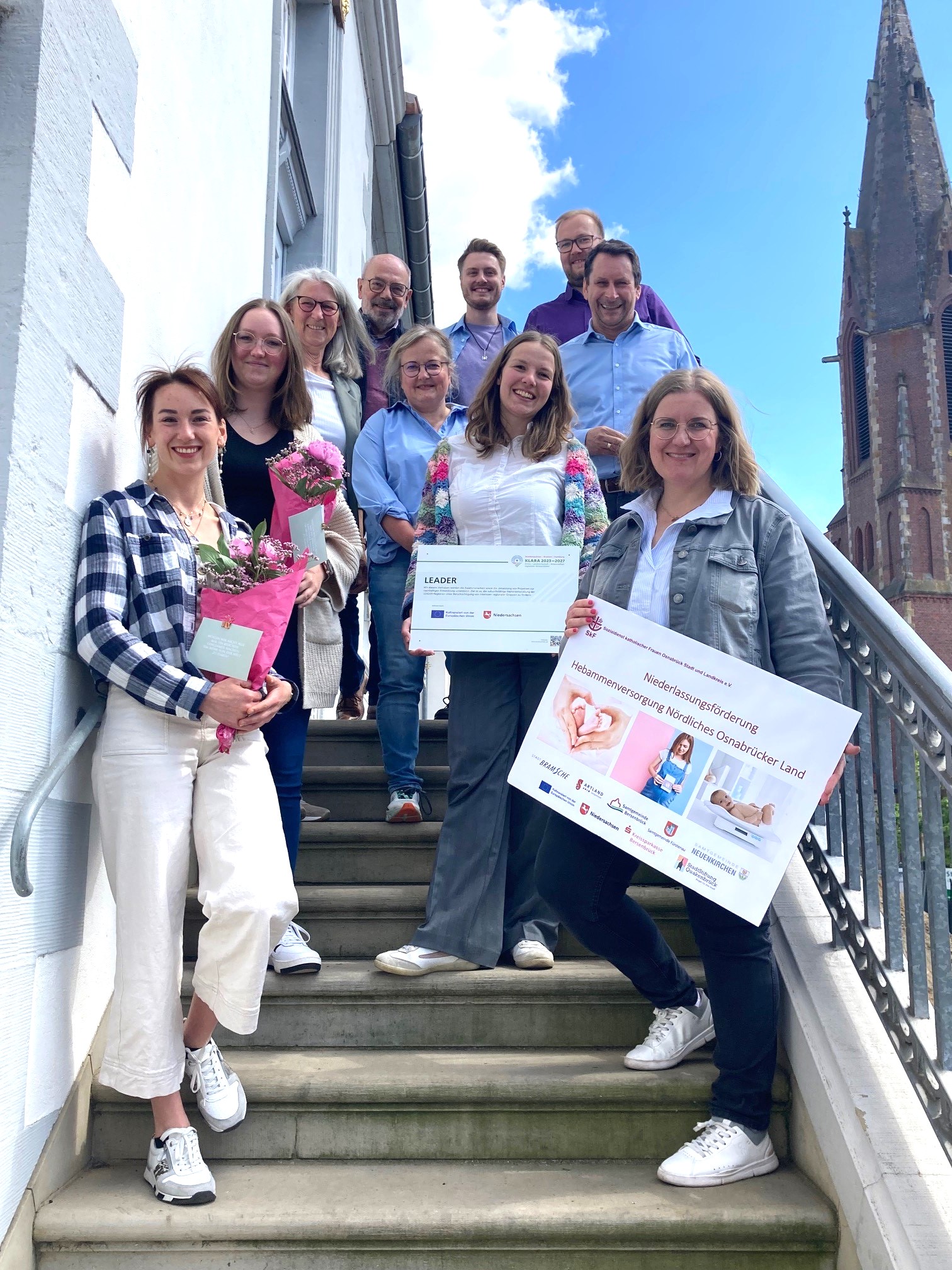 Pressefoto Hebammenprojekt Hochformat Das Team der Hebammenversorgung steht auf der Treppe