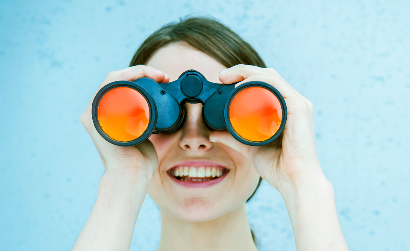 Eine Frau schaut durch ein Fernglas.