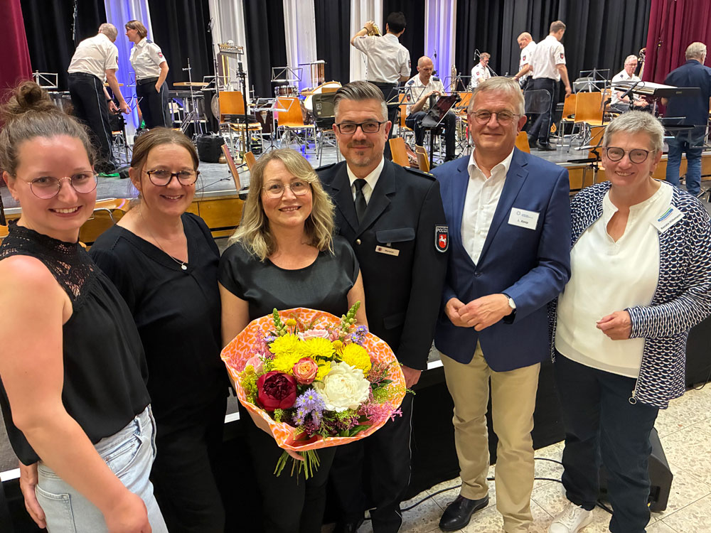 Die Organisator:innen stehen mit Blumenstrauß vor dem Orchester.